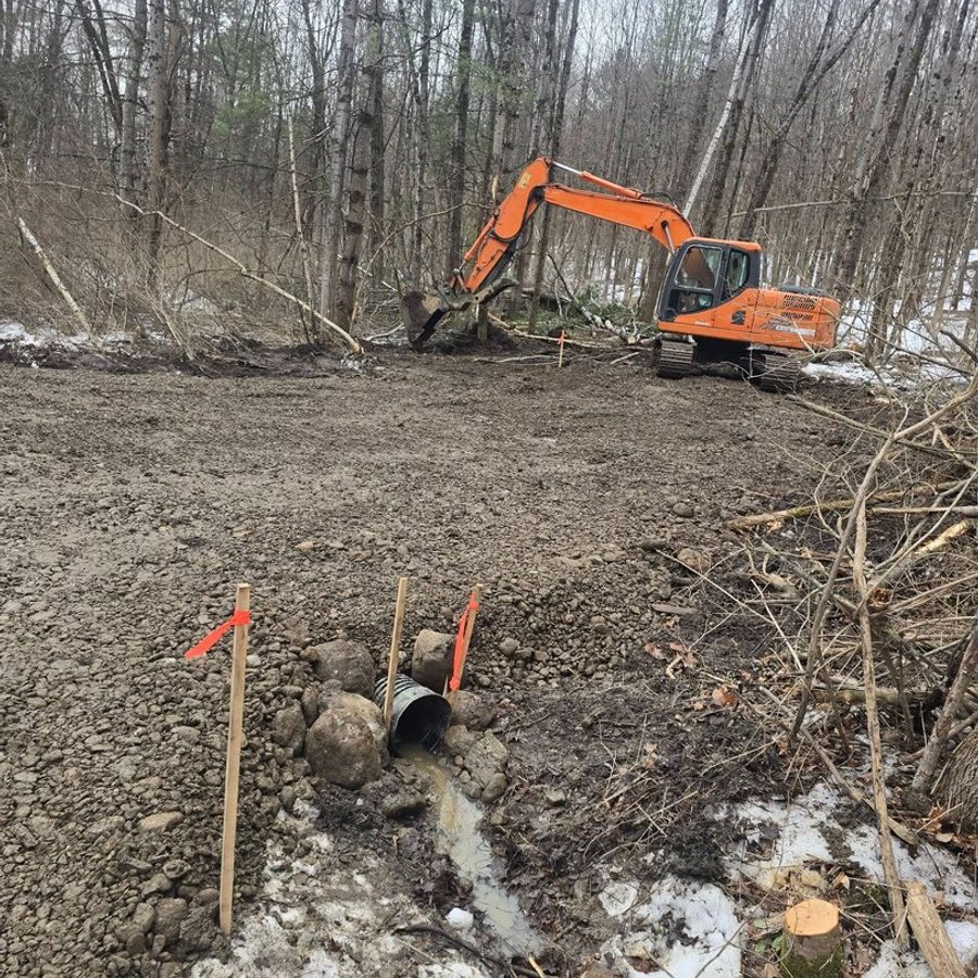 New culvert pipe set with grade stakes on a cleared site