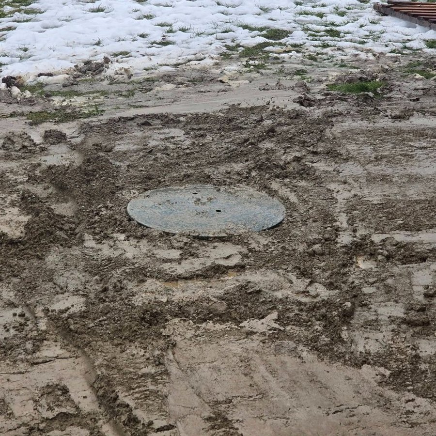 Septic tank cover set at grade in a freshly regraded yard